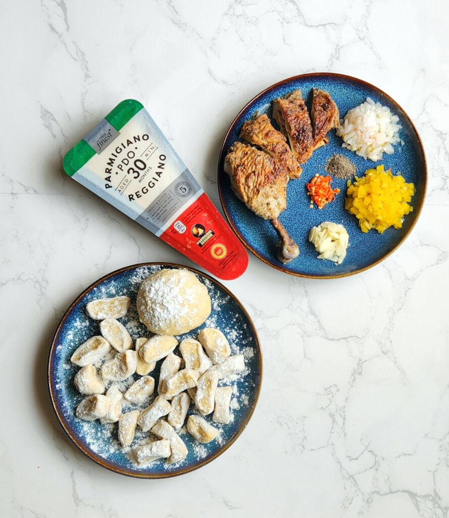 Gnocchi dough, parmesan, roasted chicken leg, cut onions and other ingredients on a plate. 