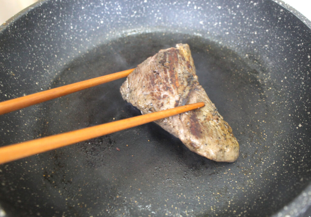 beef being cooked in a pan 