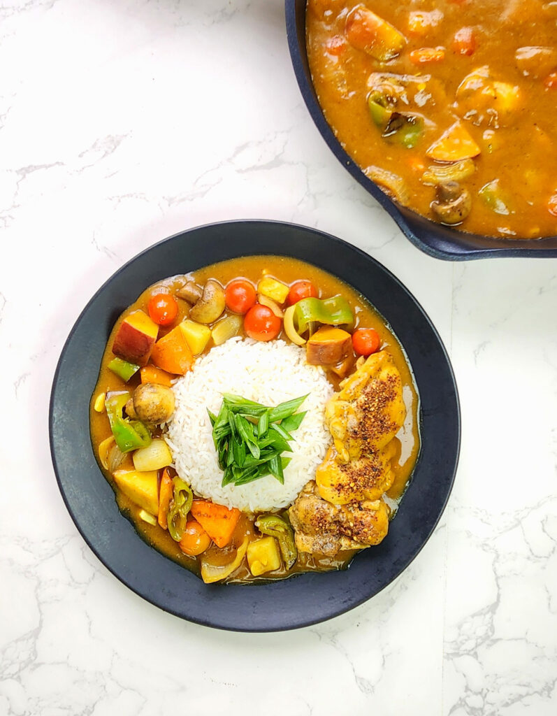 Japanese curry in a plate with white rice, with a pan of Japanese curry in the corner 