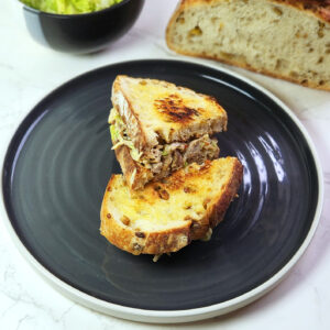 Chef's special Chicken Mayo Sandwich on a plate with sourdough loaf and lettuce in the background