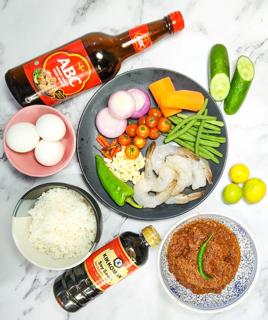 Nasi Goreng - Indonesian fried rice ingredients - soy sauce, sweet soy sauce, white rice, carrots, beans, tomatoes, prawns, chillies, onions, eggs, cucumber, lime and sambal