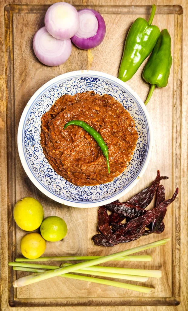 Indonesian sambal terasi in a bowl with ingredients lemongrass, onions, lime, dried red peppers