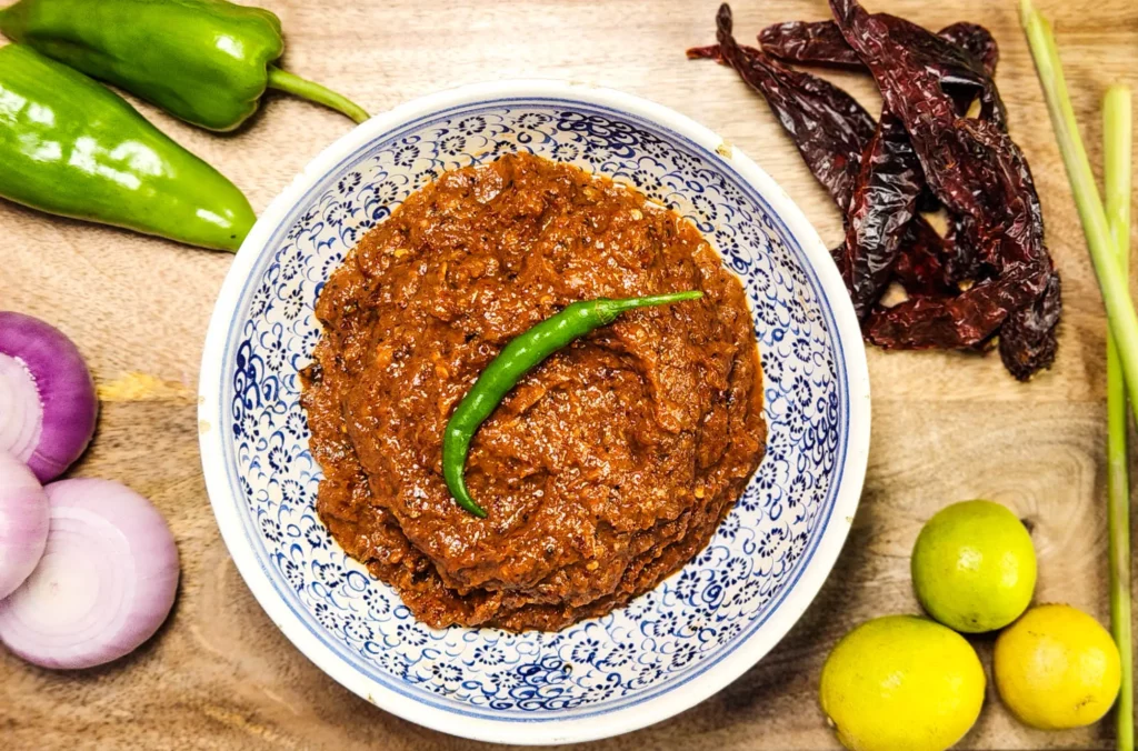 Indonesian sambal terasi in a bowl with ingredients lemongrass, onions, lime, dried red peppers