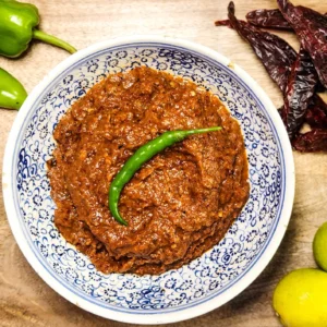 Indonesian sambal terasi in a bowl with ingredients lemongrass, onions, lime, dried red peppers