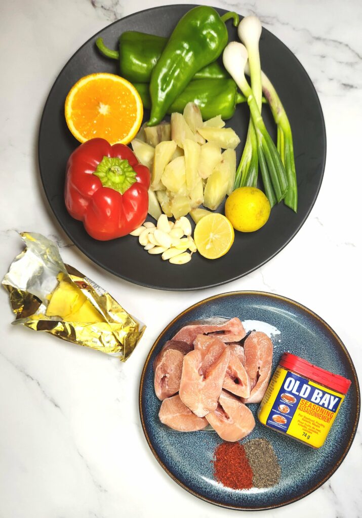 Cajun style blackened fish and sweet potato hash ingredients. Fish fillets with Cajun seasoning and pepper, sweet potato hash ingredients with bell peppers, spring onions, garlic and limes and oranges