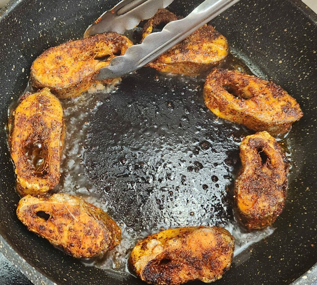 Cajun style blackened fish fillets frying in a pan of hot oil