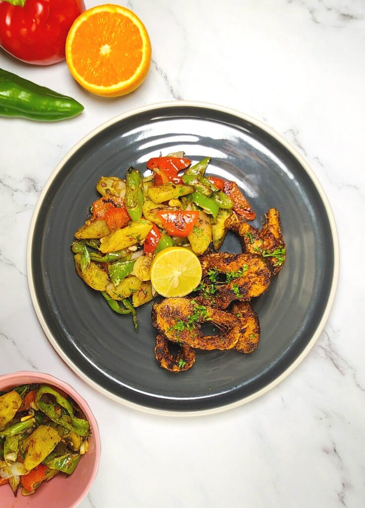 Cajun style blackened fish with sweet potato hash, bell peppers, lime and orange wedge