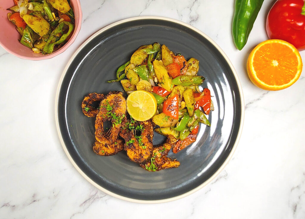 Cajun style blackened fish with sweet potato hash, bell peppers, lime and orange wedge