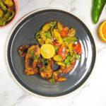 Cajun style blackened fish with sweet potato hash, bell peppers, lime and orange wedge