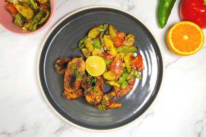 Cajun style blackened fish with sweet potato hash, bell peppers, lime and orange wedge