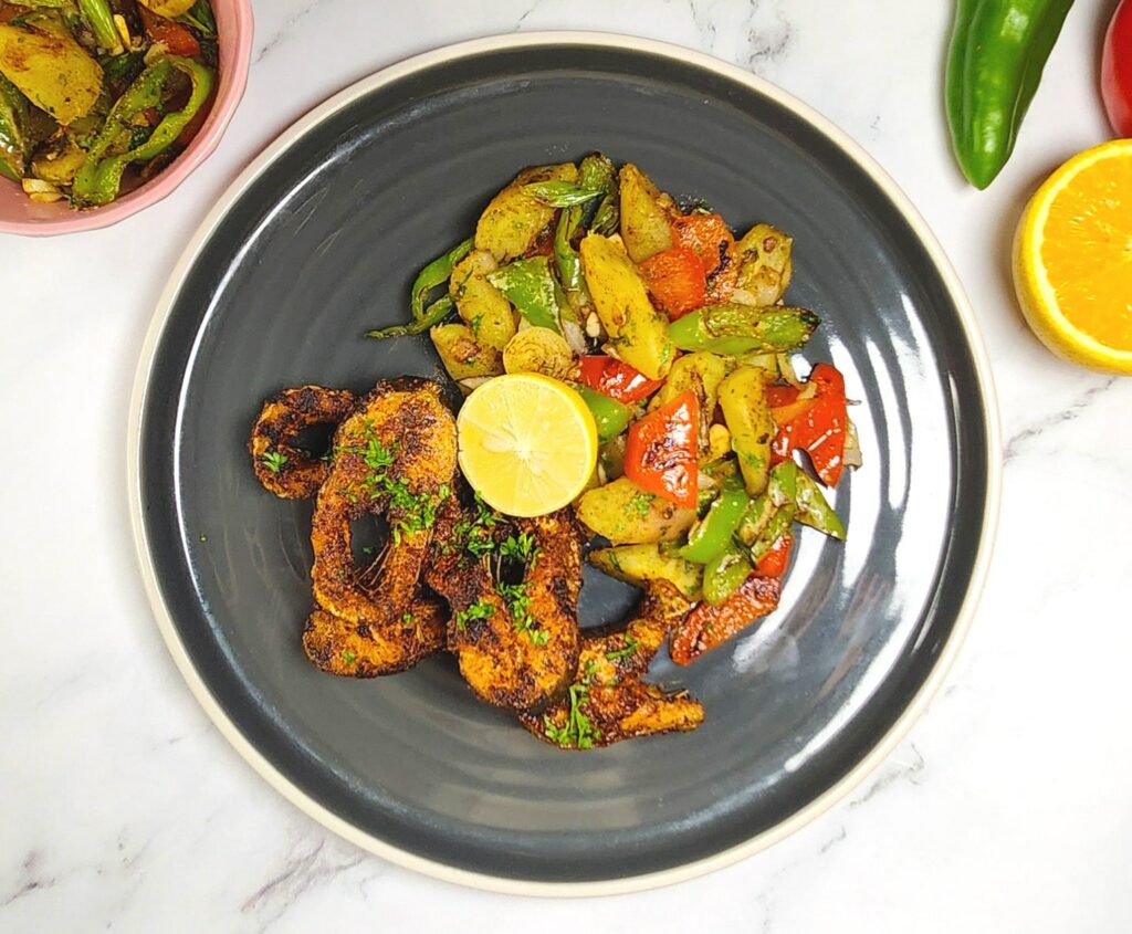 Cajun style blackened fish with sweet potato hash, bell peppers, lime and orange wedge