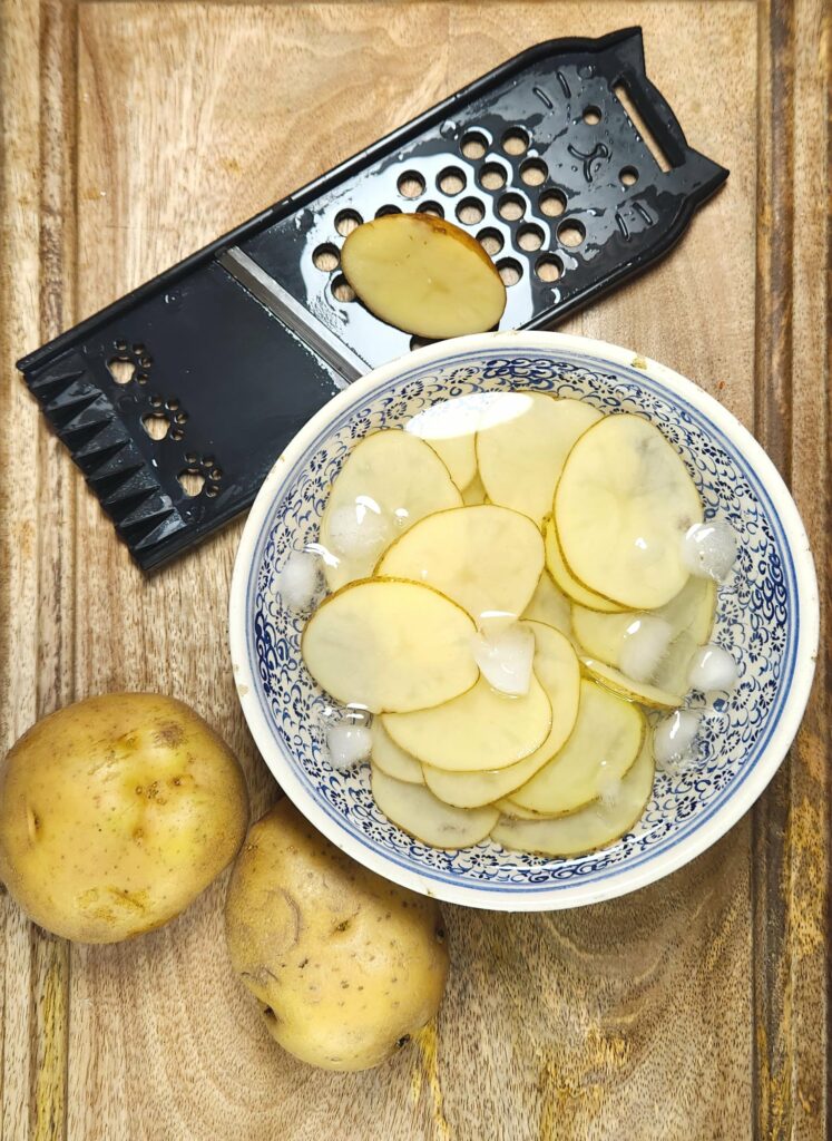 honey butter chips whole potatoes, mandoline slicer and potato slices in a ice water bath