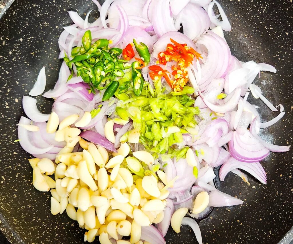 Indonesian sambal terasi ingredients in a pan lemongrass, onion, garlic and chillies