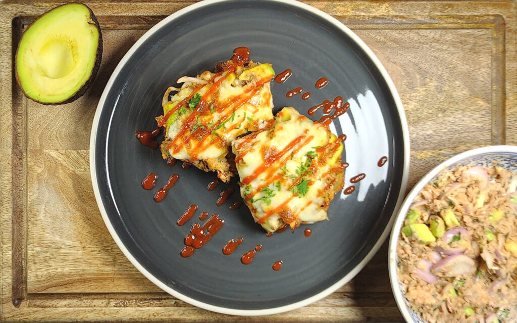 tuna melt on toast drizzled with sriracha, with cut avocado and tuna mix