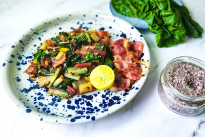 Sauteed Swiss chard with bacon on a plate with lime and salt