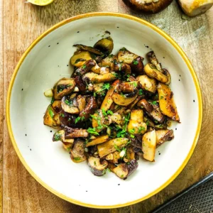 Garlic Butter Mushrooms in a plate with parsley on top, assorted mushrooms, lime and nutmeg