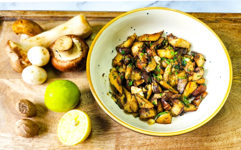 Garlic Butter Mushrooms in a plate with parsley on top, assorted mushrooms, lime and nutmeg