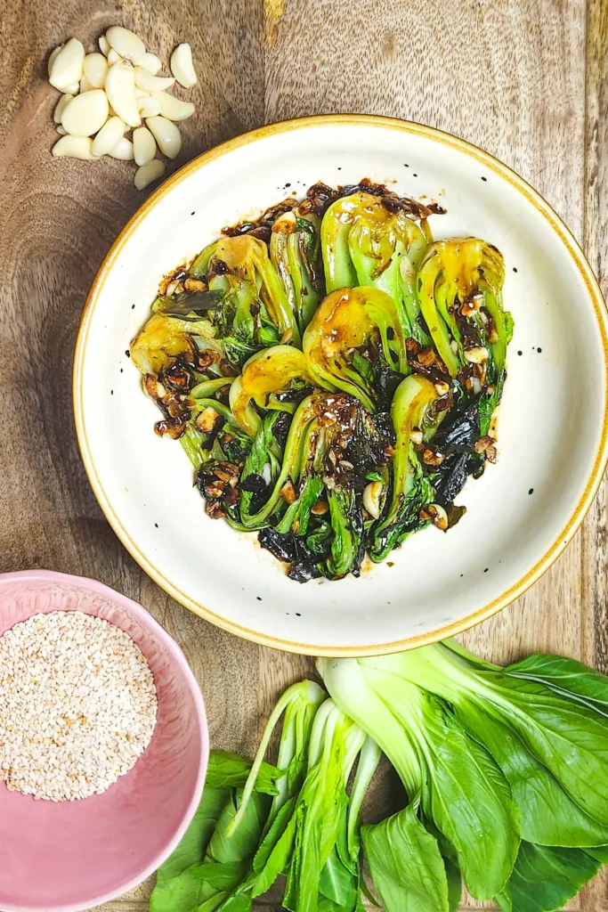 easy stir fried bok choy with hoisin sauce in a bowl with garlic, sesame seeds and baby bok choy