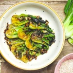 easy stir fried bok choy with hoisin sauce in a bowl with garlic, sesame seeds and baby bok choy