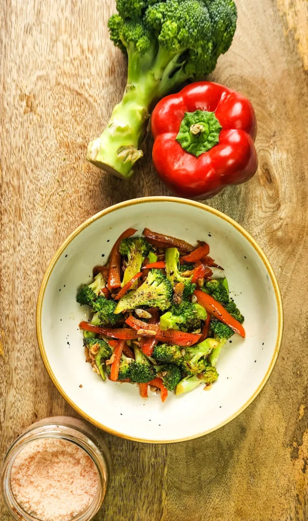 chargrilled garlic broccoli and peppers in a bowl with bell pepper, broccoli and salt on the side