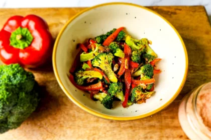 chargrilled garlic broccoli and peppers in a bowl with bell pepper, broccoli and salt on the side