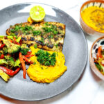 parsley butter grilled fish on a plate with pumpkin mash and chargrilled broccoli and peppers and lime.