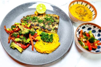 parsley butter grilled fish on a plate with pumpkin mash and chargrilled broccoli and peppers and lime.