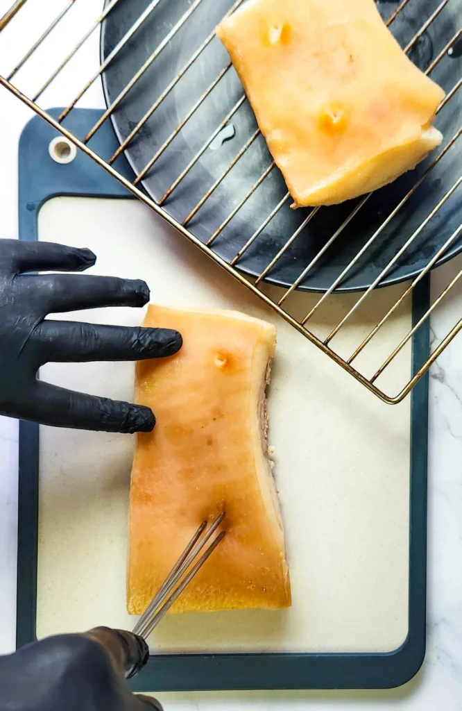 Chinese crispy pork belly boiled being scored with a skewer