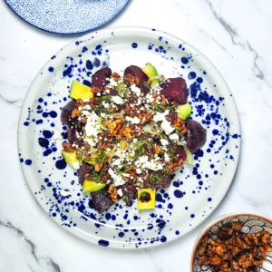 beetroot salad with goats cheese and candied walnuts in a plate with leeks and avocado