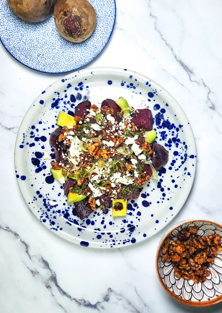 beetroot and feta salad with candied walnuts and balsamic glaze in a plate with leeks and avocado