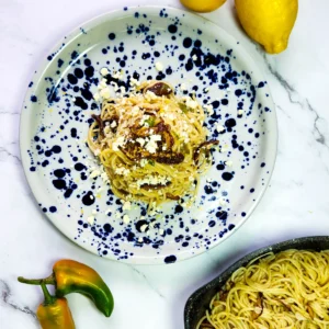 lemon butter linguine in a plate with lemons, goat's cheese and shiitake mushrooms, peppers