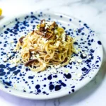 lemon butter linguine in a plate with lemons, goat's cheese and shiitake mushrooms, peppers