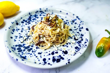 lemon butter linguine in a plate with lemons, goat's cheese and shiitake mushrooms, peppers