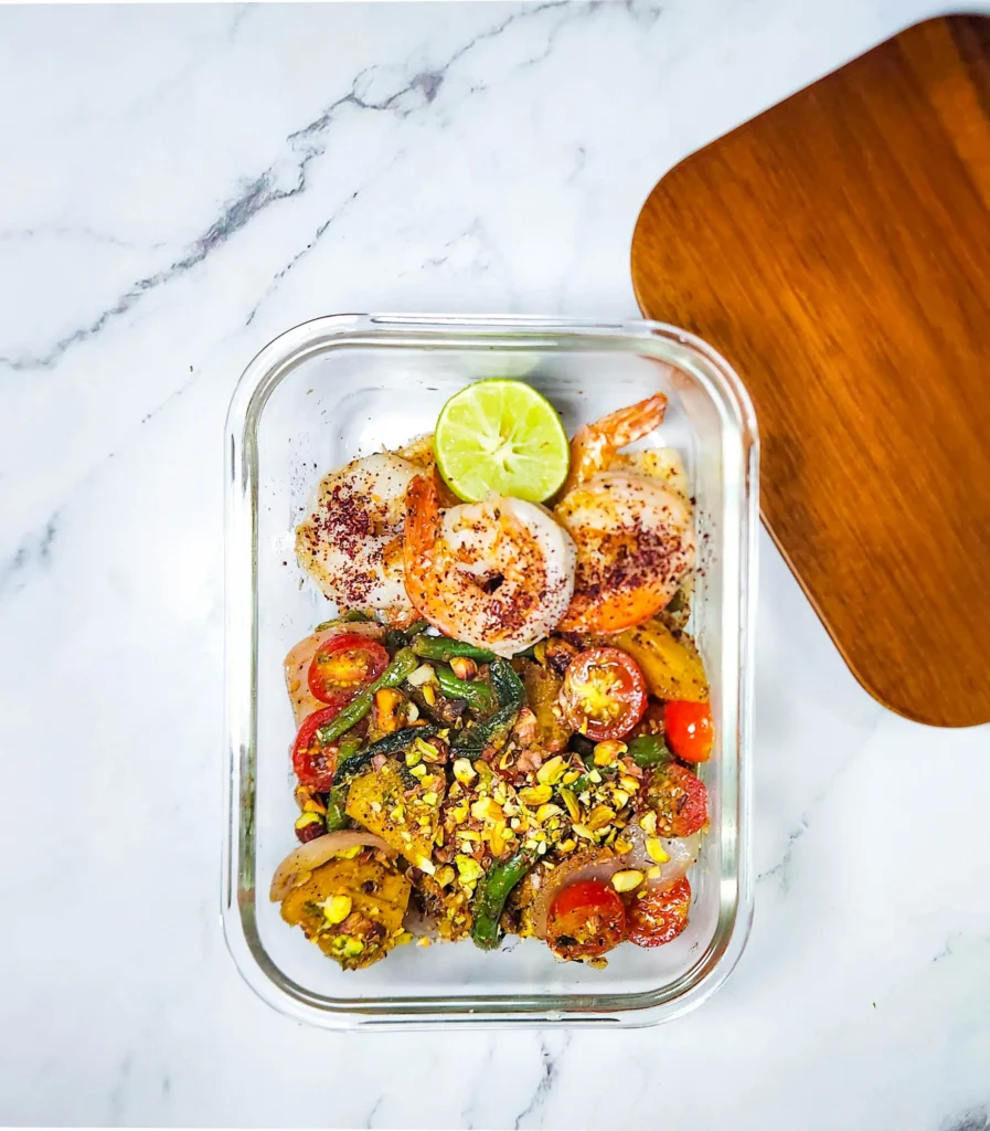 Roasted pumpkin salad in a lunchbox with cherry tomatoes, pistachios, beans, onions, pumpkin, butter, garlic and sage leaves. Sumac, mustard sauce, lime, honey and grapefruit dressing. Grilled prawns and lime.