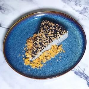 black sesame cheesecake slice on plate with biscuit base